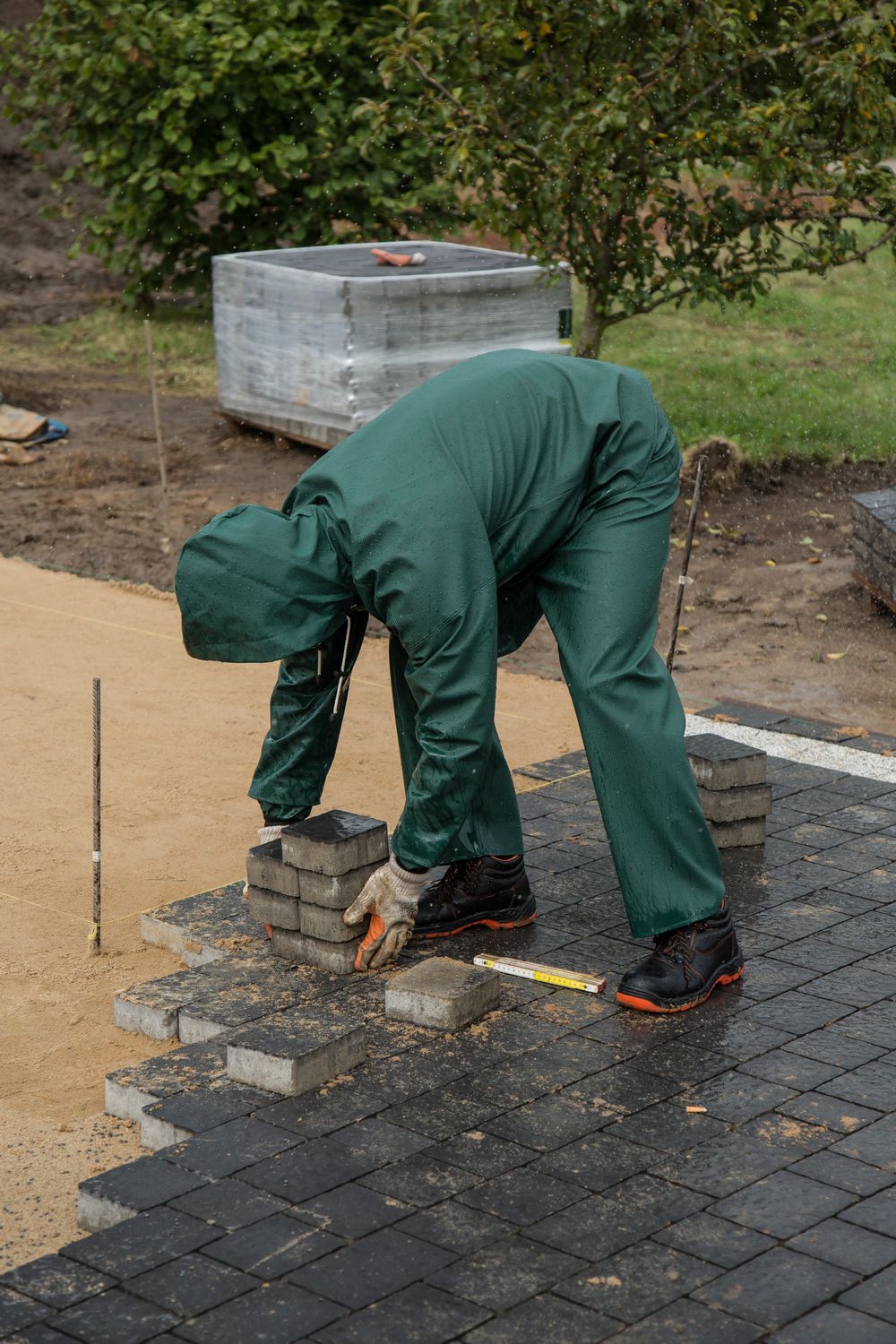 A worker setting paving stones into a bed of sand