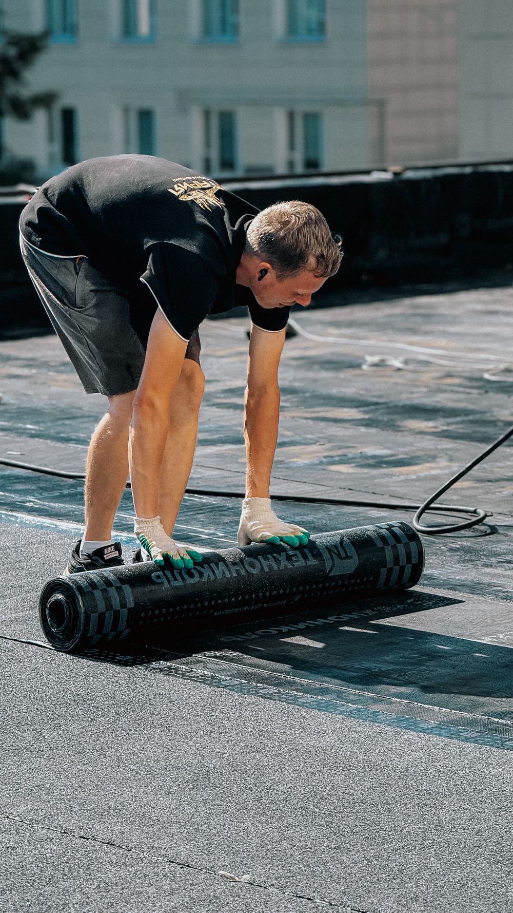 A worker rolling out membrane on a flat roof